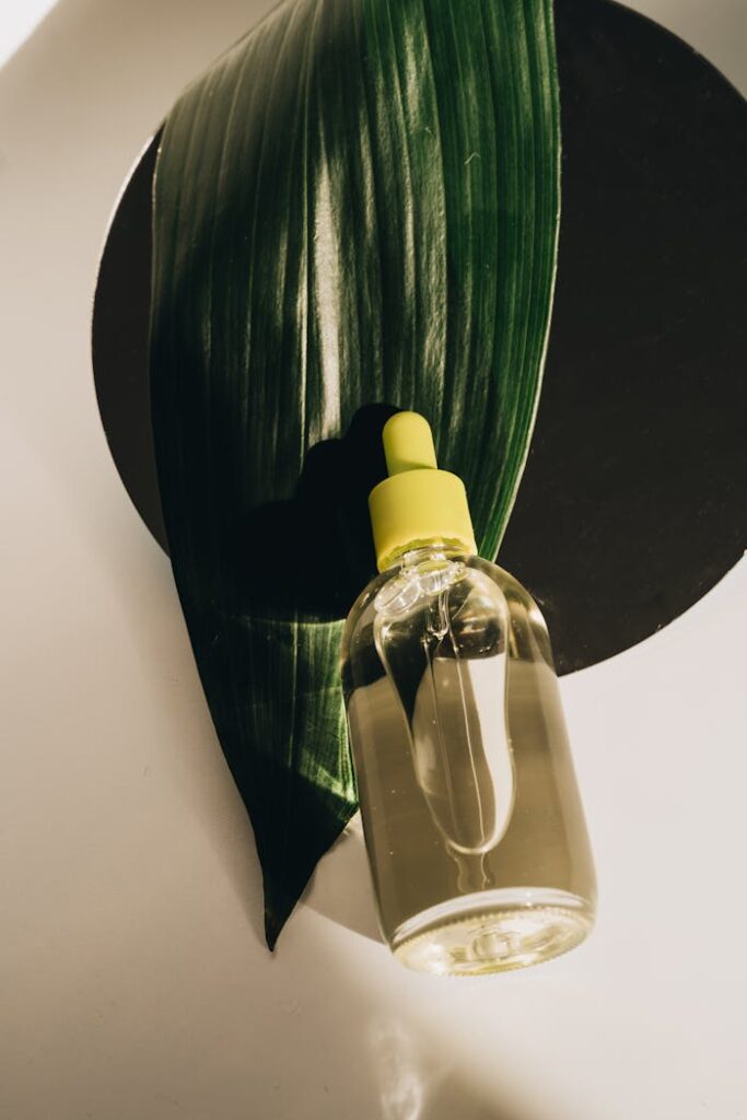 A clear glass dropper bottle on a green leaf creating a natural, soothing setting.